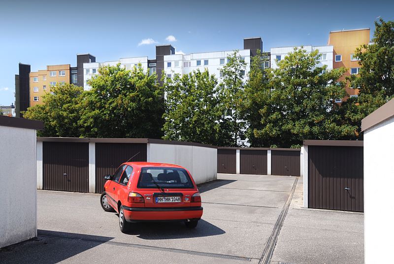 Fotos aus dem Hamburger Bezirk Mitte, Stadtteil Wilhelmsburg Kirchdorf Sd.   127_9015 Garagenanlage in der Wohnsiedlung Kirchdorf Sd. Ein roter PKW verlsst seinen Stellplatz und wird zur Strasse gefahren. Im Hintergrund Hochhuser am Karl-Arnold-Ring. In der Hochhaus-Siedlung Kirchdorf Sd, die in den 1980er Jahren errichtet wurde, leben ca. 5700 Menschen. www.fotos- hamburg.de