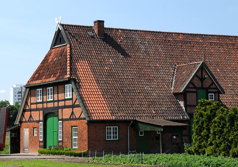 Bauernhaus mit Fachwerk + Ziegeldach  Bilder aus dem Stadtteil Hamburg Wilhelmsburg,  Stillhorn   132_9137 Fachwerkbauernhaus in Hamburg Stillhorn; das Scheunentor ist grn gestrichen auf dem Dachfirst die regionaltypischen sich ansehenden Pferdekpfe als Giebelschmuck. Links im Hintergrund ist ein Ausschnitt eines Hochhauses der Grosssiedlung Kirchdorf-Sd zu erkennen. www.fotos- hamburg.de