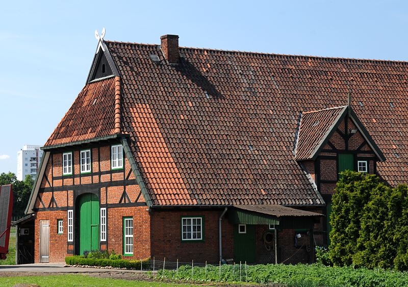 Bauernhaus mit Fachwerk + Ziegeldach  Bilder aus dem Stadtteil Hamburg Wilhelmsburg,  Stillhorn   132_9137 Fachwerkbauernhaus in Hamburg Stillhorn; das Scheunentor ist grn gestrichen auf dem Dachfirst die regionaltypischen sich ansehenden Pferdekpfe als Giebelschmuck. Links im Hintergrund ist ein Ausschnitt eines Hochhauses der Grosssiedlung Kirchdorf-Sd zu erkennen. www.fotos- hamburg.de