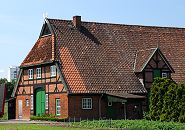 132_9137 Fachwerkbauernhaus in Hamburg Stillhorn; das Scheunentor ist grn gestrichen auf dem Dachfirst die regionaltypischen sich ansehenden Pferdekpfe als Giebelschmuck. Links im Hintergrund ist ein Ausschnitt eines Hochhauses der Grosssiedlung Kirchdorf-Sd zu erkennen. www.fotos- hamburg.de