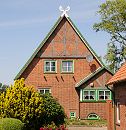 133_9135 Bauernhaus mit Fachwerkgiebel in Hamburg Stillhorn; im Vorgarten blhen Pfingstrosen, die Fensterrahmen sind in regionaltypischem Grn gestrichen. Auf dem Dach zwei Pferdekpfe als Giebelschmuck.