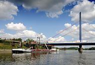 143_0594 An der Anlegestelle Georgswerder liegt ein Tankschiff und wird ber ein Schlauchsystem entladen. Autobahnbrcke mit Polygon und Seilen; auf der A1 ber die Norderelbe fahren Lastwagen; im Hintergrund die Schornsteine vom Kraftwerk Tiefstack.