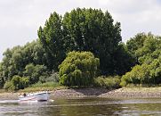 144_0601 Das Ufer der Norderelbe Hhe Spadenlander Busch / Goetjensort ist dicht bewachsen - bis dicht an das Wasser stehen Weiden und Pappeln. Bei Niedrigwasser ist die Uferbefestigung aus Steinen zu sehen, die ein Absplen des Ufers verhindern soll. Ein Motorboot fhrt elbabwrts Richtung Hamburg.