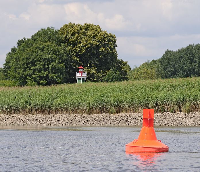 Hamburg-Fotografien - Bezirk Hamburg Mitte; Sderelbe Bunthuser Spitze Fahrwassertonne Backbord - Leuchtfeuer Bunthuser Spitze 1476_0645  An der Bunthuser Spitze teilt sich der Elblauf in die Norderelbe, die an den St. Pauli Landungsbrcken vorbeifhrt und in die Sderelbe, die an Harburg entlang am Khlbrand wieder mit der Norderelbe zusammenfliesst. Das Leuchtfeuer Bunthaus hat die Schifffahrt ab 1914 bis 1977 mit einem Rundumfeuer auf die Fahrwassertrennung hingewiesen. Der Leuchtturm aus Holz hat eine Hhe von ca. 7m; die historische Leuchtfeueranlage ist als letztes Leuchtfeuer dieser Bauweise seit 2005 unter Denkmalschutz. Im Vordergrund eine rote Fahrwassertonne, die auf die Backbordseite des Fahrwassers hinweist.