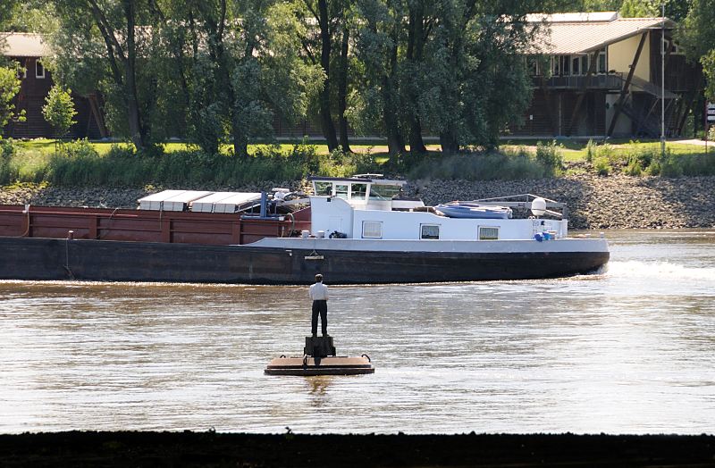 Hamburgbilder aus Hamburg-Mitte; Sderelbe bei Wilhelmsburg / Stillhorn Binnenschiff auf der Elbe - "Mann auf Boje"  unter der Autobahnbrcke  158_0968  Blick vom Ufer der Sderelbe bei Hamburg Stillhorn. Die Holzskulptur, die zu dem Gesamtkunstwerk  "Vier Mnner auf Bojen" gehrt, steht auf der Boje und blickt zu einem Binnenschiff, dass gerade aus der Reiherstiegschleuse in die Elbe eingefahren ist. Die Abdeckung des Laderaums ist geffnet - das Schiff fhrt ohne Ladung.