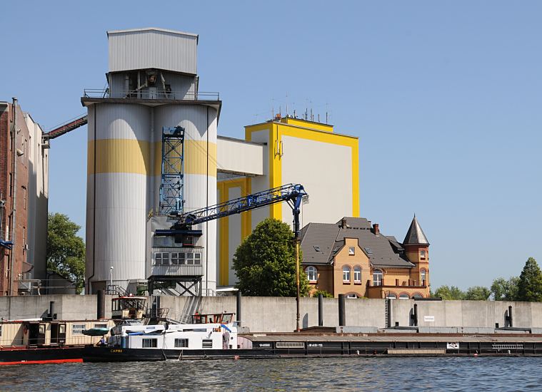 Bilder aus dem Hamburger Bezirk Mitte - Stadtteil Wilhelmsburg - Reiherstieg  167_96666 Diamant-Mehl Getreidesilo + Getreidemhle am Reiherstieg - ein Binnenschiff liegt an der Kaimauer; seine Fracht wird ber einen Saugrssel gelscht und in das Silo transportiert. Hinter der Flutschutzmauer die Grnderzeit-Villa des Erbauers der Diamant-Mhle Georg Plange - die Villa mit den gelben Klinkern und dem Erkerturm wurde 1897 erbaut.