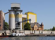 167_9666 Diamant-Mehl Getreidesilo + Getreidemhle am Reiherstieg - ein Binnenschiff liegt an der Kaimauer; seine Fracht wird ber eine Sauganlage gelscht und in das Silo transportiert. Hinter der Flutschutzmauer die Grnderzeit-Villa des Erbauers der Diamant-Mhle Georg Plange - die Villa mit den gelben Klinkern und dem Erkerturm wurde 1897 erbaut.