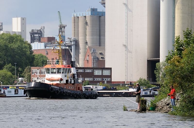 Hamburg Bilder aus den Stadtteilen, Bezirk HH-Mitte - Wilhelmsburg - Reiherstieg. Hafenschlepper BUGSIER 18 auf dem Reiherstieg 170_0829 Der Schlepper BUGSIER 18 fhrt auf dem Reiherstieg; auf dem anderen Ufer des Hamburger Wasserwegs, der die Sderelbe und Norderelbe verbindet -  Silogebude auf der HOHEN SCHAAR. Diese Elbinsel gehrt auch zu dem Stadtteil Wilhelmsburg. Rechts stehen Angler an der Mndung des Schmidt-Kanals in den Reiherstieg - sie haben mehrere Angeln ausgelegt und warten auf einen Fang.