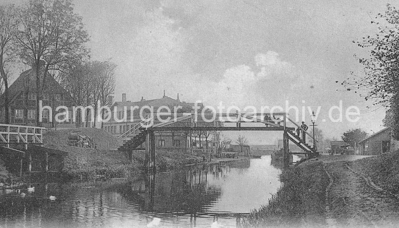 Bilder aus den Hamburger Bezirken -  Hamburg Mitte, Stadtteil Wilhelmsburg  historisches Foto vom Ernst-August-Kanal ca. 1890, Fussgngerbrcke  58_247 alstes Bild vom Ernst-August-Kanal - eine Fussgngerbrcke aus Holz verbindet die beiden Kanalufer; Wege fhren am Ufer entlang. Hinter Bumen steht ein Fachwerkhaus und ein Grnderzeit-Wohnhaus. Im Hintergrund die Schleuse zum Reiherstieg, davor liegt eine Schute am Steg, rechts fhren Karrenspuren zu einem Lagerhaus. www.fotograf- hamburg.com