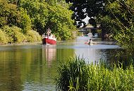 59_9364 Der Ernst-August-Kanal ist ein interessantes Freizeitrevier in Hamburg Wilhelmsburg. Ein Motorboot fhrt den Kanal Richtung Ernst-August-Schleuse, Kanuten paddeln ihr Kanu den Kanal hinauf. Im Vordergrund ein Blesshuhn und Schilf am Kanalufer. www.fotograf- hamburg.com