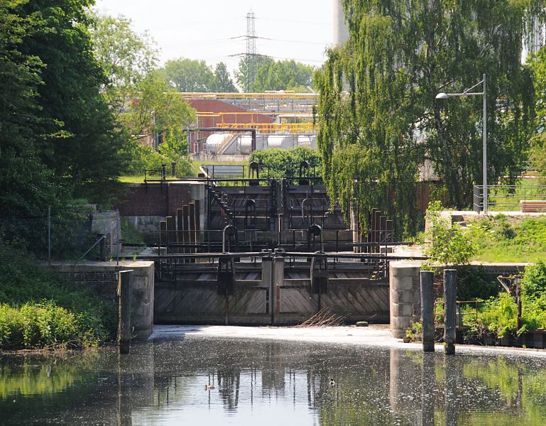 Bilder aus den Hamburger Bezirken - Schleuse am Veringkanal - Industrieanlagen Reiherstieg Wilhelmsburg, Hamburg-Mitte 80_9392 Blick zur Schleuse am Veringkanal; die alte Schleuse mit den Holztoren wurde 1896 errichtet und 2008 restauriert. Ein Schleusenwrter betreibt die historische Schleusenanlage von Hand - und ermglicht so die Zufahrt zu dem tidenabhngigen Reiherstieg und der Elbe. Im Hintergrund sind Industrieanlagen am Ufer des Reiherstiegs zu erkennen. www.fotograf-hamburg.de