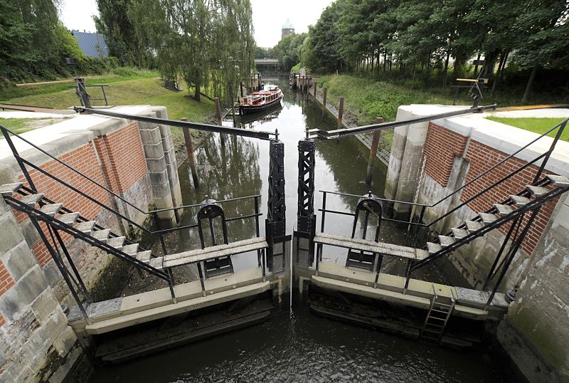 Bilder aus dem Stadtteil Wilhelmsburg, Bezirk Hamburg-Mitte historische Schleuse am Veringkanal - Barkasse in der Schleusenkammer 82_7321 Schleusenkammer der historischen Veringkanal-Schleuse; die Schleuse wurde 1896 errichtet und wird von Hand betrieben. Der Wasserstand ist auf den Pegel des Veringkanals gebracht, das Schleusentor ist dort geffnet und eine Barkasse legt vom Ponton ab. Im Hintergrund der Wilhelmsburger Wasserturm.  Die Restaurierung der Schleuse wurde 2008 abgeschlossen. www.fotograf-hamburg.de