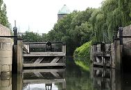 83_7342 Eines der Holztore der historischen Veringkanal-Schleuse ist geffnet - die Schleuse wurde 1896 errichtet und wird von Hand betrieben. Die Anlage wurde 2008 restauriert. Weiden stehen am Ufer des Kanals - im Hintergrund die Kuppel vom Wilhelmsburger Wasserturm und die Spitzen der Kirchtrme der St. Bonifatius-Kirche. www.fotograf- hamburg.de