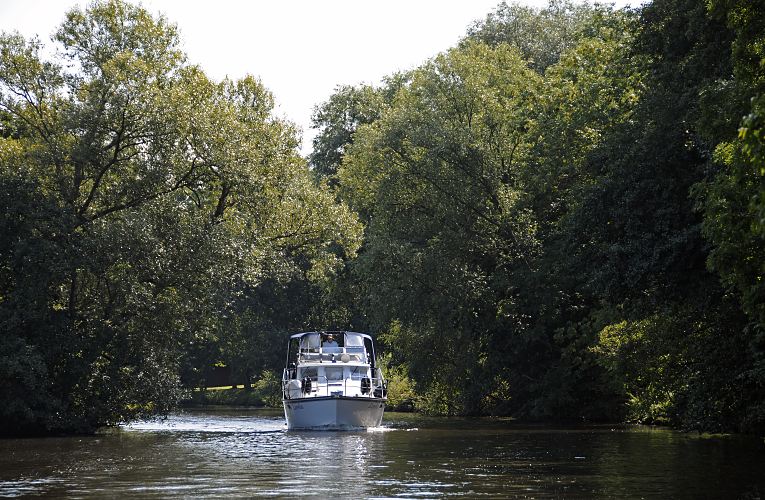 der Hamburger Bezirk Bergedorf in Fotos - Motoryacht auf der Doveelbe. 11_21581 Eine weisse Motoryacht fhrt flussabwrts auf der Dove-Elbe; hohe Bume stehen am Flussufer, die ste wachsen bis zur Mitte des Flusse und bilden fast ein grnes Dach.  www.hamburg-fotograf.com