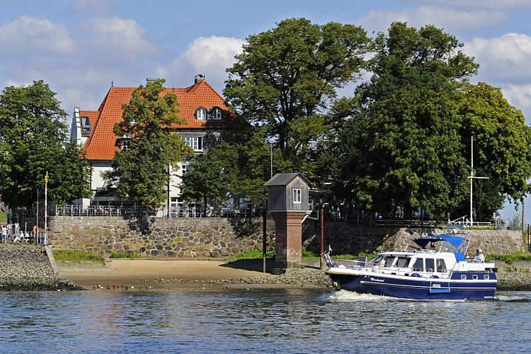 Fotos von Hamburg - Bilder Bezirk Bergedorf,  Fotografie Stadtteil Kirchwerder - Zollenspieker Fhrhaus  11_21612 Eine Motoryacht fhrt auf der Elbe flussabwrts - der Freizeitkapitn sitzt unter dem Persenning-Sonnenschutz im Fhrerstand des Motorboots. Das Boot passiert gerade das Zollenspieker Fhrhaus und das Pegelhaus am Ufer der Elbe. www.bilder-hamburg.de