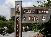 11_21637  Handgeschnitztes Hinweisschild zum Mhlenladen und Cafe bei der Riepenburger Mhle. Auf der Strassen fahren Inlineskater und ein Fahrrad. Die Strassen durch die Drfer der Vier- und Marschlande werden am Wochenende hufig von den Hamburger Ausflglern fr dieses sportliche Freizeitvergngen genutzt. www.hamburg-bilder.org