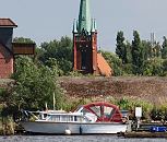 11_21647  Der Kirchturm der St. Nikolaikirche in Hamburg Moorfleet wurde 1885 errrichtet. Im Vordergrund ein Sport- boot mit herunter geklapptem Verdeck und Bootsstege im Holzhafen; dahinter ist der Deich zu erkennen. www.hamburg-bilder.org