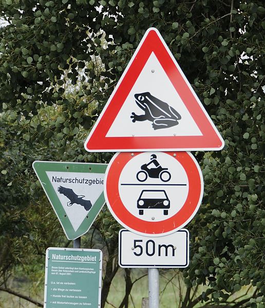 Foto von Schildern, Naturschutzgebiet / Krtenwanderung   11_21662  Hinweisschild, das ein Naturschutzgebiet beginnt - zum Schutz der Lebensrume gefhrdeter Tier- und Pflanzenarten drfen nur die ausgewiesenen Wege benutzt werden. Ein weiteres Schild weist auf die Mglichkeit von Krtenwanderung hin; jedes Frhjahr beginnen die Molche, Frschen und Krten ihre Laichwanderung zu ihren Laichgebieten; fr Autos und Motorrder ist die Zufahrt gesperrt. www.bildarchiv-hamburg.com