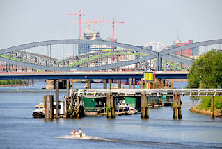 01132_2634 JEhemaliger Zollanleger, Liegeplatz der Zollschiffe in Hamburg Rothenburgsort / Entenwerder; Holzgebude auf den Pontons - Arbeitsschiffe. Eine Wassertreppe verbindet die Anlage mit dem Ufer von Entenwerder; im Hintergrund die Norderelbbrcke und die Freihafenelbbrcke, die die Zollgrenze zum Hamburger Freihafengebiet bildete.