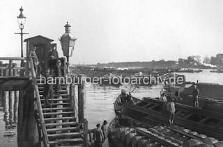 01144_45346 Zollstation Entenwerder in Hamburg Rothenburgsort an der Norderelbe - Binnenschiffe liegen in Paketen auf der Elbe; im Vordergrund stehen die Schiffer auf ihren Booten. Der Elblnder Kahn im Vordergrund hat Holzfsser geladen. Auf der Holztreppe stehen Zllner und Schiffer mit Peekhaken / Bootshaken.