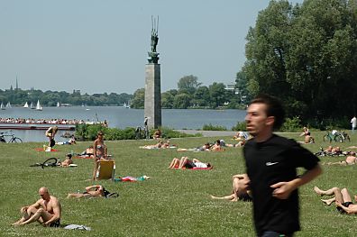 011_14492 - Alsterwiesen am Schwanenwik; Menschen liegen auf der Alsterwiese und sonnen sich; auf der Aussenalster macht ein Altercabrio seine Alsterrundfahrt - ein Jogger luft vorbei. 