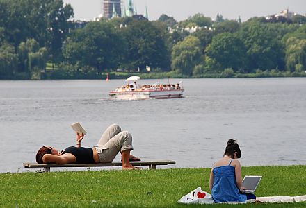 011_15808 - Entspannung an der Aussenalster - es wird mit dem Labtop auf der Alsterwiese gearbeitet oder auf der Bank liegend ein Buch gelesen - im Hintergrund fhrt ein Alstercabio in der Sommersonne die Hamburg Touristen auf seiner Rundfahrt ber den grossen Hamburger Binnensee. 