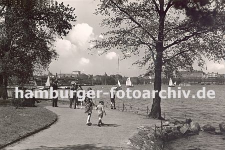 11_17421 - historisches Bild vom Alsterufer der Aussenalster ca. 1938; ein Geschwisterpaar geht hinter seinen Eltern auf dem Alsterweg kurz hinter den Lombardsbrcken - das Ufer ist mit Steinen befestigt, Segelschiffe fahren auf dem Hamburger See; im Hintergrund Gebude an der Strasse "Alsterufer".