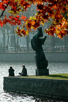 011_14200 - ein Paar sitzt in der Herbstsonne unter der Skulptur "Die Windsbraut" von Hans- Martin-Ruwoldt; rot gefrbtes Herbstlaub / Ahorn im Vordergrund