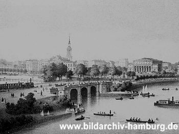 011_14204 - ein Zug fährt auf die Lombardsbrücken zu; diverse Ruderboote, Segelboote und ein Alsterdampfer fahren auf der Binnenalster; re. das Gebäude der Kunsthalle in der Bildmitte der Kirchturm der Dreieinigkeitskirche in St. Georg. (ca. 1870)