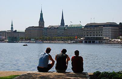 011_15923 - drei Hamburger sitzen in der Sonne an der Binnenalster und blicken Richtung Jungfernstieg. - rechts der Alsterpavillon undk lks. die Tum von der St. Katharinenkirche, der Turm vom Hamburger Rathaus und re. der Turm der Nikolaikirche - ein Ruderboot fhrt auf der Alster.