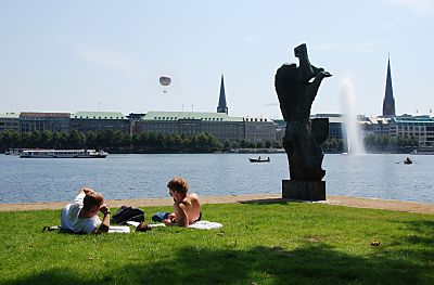 011_15927 - zwei Studenten liegen in der Sonne auf dem Rasen und studieren ihre Unterlagen, rechts die Skulptur "Die Windsbraut" von Hans- Martin-Ruwoldt. Im Hintergrund die Huser vom Ballindamm und die Trme der St. Jacobikirche Sund  St. Petrikirche. Auf der Binnenalster fahren ein Alsterschiff der weissen Flotte und Ruderboote.