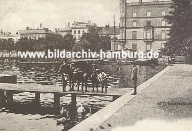 011_15931 - Kinder stehen auf dem Holzsteg an der Binnenalster bei der Lombardsbrcke und fttern Schwne, ein Segelboot liegt am Kai; dahinter Huser vom Neuer Jungfernstieg (historisches Bild ca. 1905) 