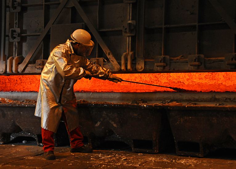 11_21451 Ein Metallarbeiter steht vor der teilweise geffneten Ofentr des Schmelzofen der Hydro Aluminiumwerken in Hamburg Finkenwerder. Der Mann trgt einen silberfarbenen Schutzmantel gegen die Hitze an seinem Arbeitspatz sowie einen Arbeitshelm mit Gesichtsschutz. Aluminium hat eine Schmelztemperatur / Schmelzpunkt von 660,32 C ( 933,47 K ) und einen Siedepunkt von 2467 C  ( 2740  K ) Die Hnde des Arbeiters am geffneten Ofen sind mit feuerfesten Handschuhen geschtzt - mit einer Metallstange berprft er die Konsistenz der Aluminiumschmelze. Industriefotos aus Hydro Aluminium Hamburg - Metallarbeiter, Aluminiumschmelze.