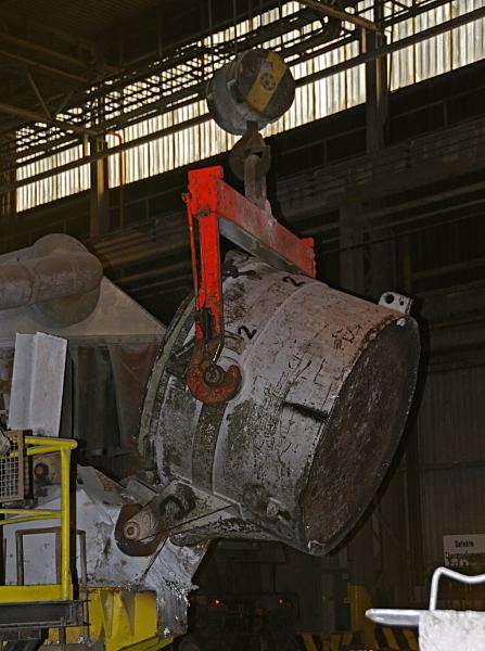 11_21452 Mit einer Krananlage, die an der Hallendecke des Industriegebäude angebracht ist, wird aus einem grossen Tiegel flüssiges Aluminium in den Schmelzofen der Hydro Aluminumwerke in Hamburg Finkenwerder eingefüllt. Industriefotografie Hydro Aluminium