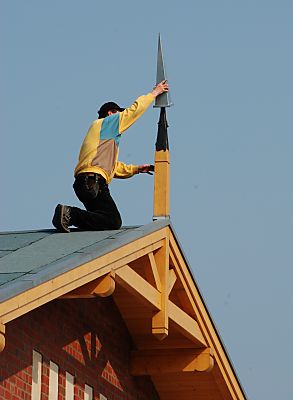 011_15418 - ein Dachdecker versieht die Giebelspitze des Gebudes mit einer Metallhlse. 