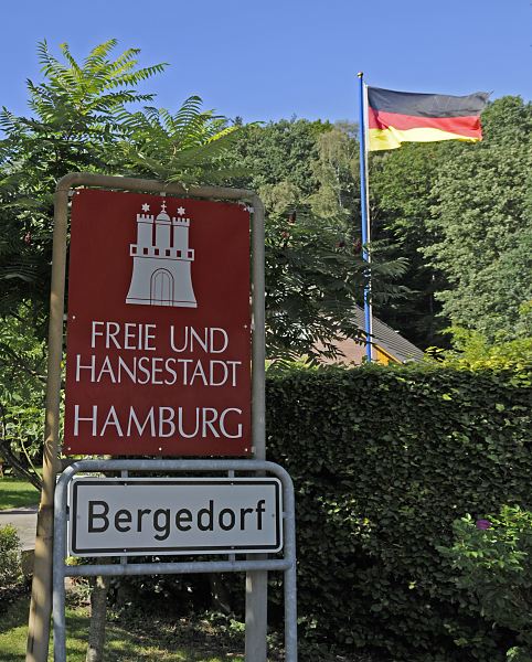 Fotos aus Hamburger Bezirken - Stadtgrenze Hamburg - 11_21460 Hamburgs sdstliche Stadtgrenze; ein rotes Schild mit weisser Schrift "Freie und Hansestadt Hamburg" weist auf die Grenze zum Stadtstaat Hamburg hin. Die Burg mit den Trmen und Zinnen ist das Wappen Hamburgs. Das weisse Schild darunter zeigt den Beginn des Hamburger Bezirks Bergedorf. www.hamburg-fotograf.com