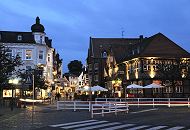 11_21486 Blick von der Alten Holstenstrasse in die Strasse Sachsentor der City Bergedorfs - die Geschfte sind in der Abenddmmerung zur "Blauen Stunde" beleuchtet. Rechts das historische Fachwerkgebude vom Gasthaus "Stadt Hamburg", das um 1550 gegrndet wurde - es befindet sich jetzt dort ein Fleischrestaurant; im Sommer knnen die Gste auf der Strasse unter Sonneschirmen sitzen und essen. www.hamburg-fotograf.com