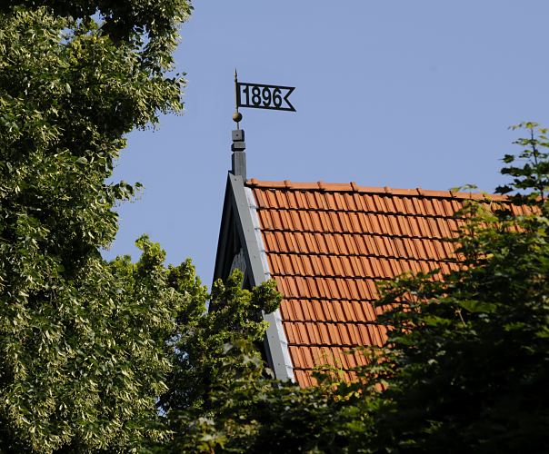 Bild Wetterfahne mit Jahreszahl - Bergedorfer Architekturfoto   11_21523 Eine Wetterfahne mit der Jahreszahl 1896, dem Baujahr des Gebudes, ziert das Dach des Hauses im Villenviertel von Hamburg Bergedorf. Ende des 19.  Jahrhunderts wurde begonnen, das sogenannte Villenviertel zu bebauen -  wohlhabende Hamburger und Bergedorfer Brger lieen dort ihre reprsentativen Wohnhuser errichten. Es entstanden Stadthuser, die die unterschiedlichen Stile der Architektur ausdrckten - neben der Bauform der Grnderzeit wurde auch der Jugendstil architektonisch umgesetzt oder Wohnhuser in der Architektur der neuen Sachlichkeit gebaut.  www.hamburg-fotograf.com