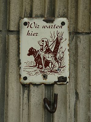 011_14320 Schild fr Hunde an einer gekachelten Ladenwand: ' Wir warten hier ' und zwei angeleinte Hunde im Stil der 50er. 