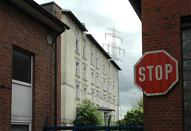 04_23420 - Blick durch Industriearchitektur aus Backstein zum Schlossgebude; dahinter der Mast der elektrischen Hochspannungsleitungen, die ber die Schlossinsel verlaufen - re. ein Stop-Schild.