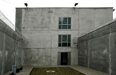 04_22882 - Blick über den Freigang-Hof zum Gefängnisgebäude; links sind zwei Bänke als Sitzgelegenheit montiert - in der Mitte ist eine freundliche Grünfläche angelegt.