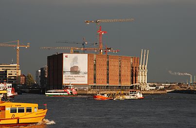 011_15421 das denkmalgeschützte Gebäude vom Kaispeicher in der Abendsonne; auf der Elbe fahren die Elbfähren ihre Passagiere - im Hintergrund die Baukräne der Hafencity.