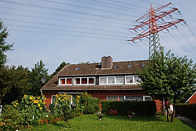 011_15999 - Mehrfamilienhaus in der Strasse Mmmel- mannsberg; Sonnenblumen blhen im Garten - im Hintergrund ein Hochspannungsmast mit Stom - berlandleitungen. 