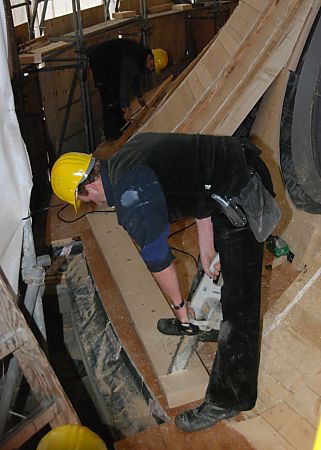 011_17353 - Bauarbeiten am Holzgerst - mit einer Motorsge trennt ein Bauarbeiten einen Holzbalken, damit er in den Ausschnitt am Fenster der Kuppel einge- passt werden kann.