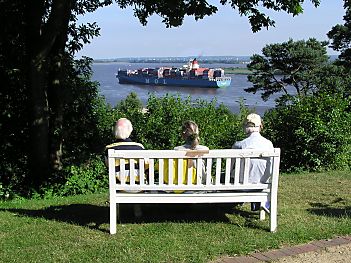011_14413 - drei Ausflgler sitzen auf einer Holzbank am Falkensteiner Ufer und beobachten ein einlaufendes Containerschiff unten auf der Elbe.