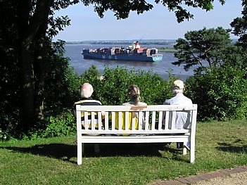 011_14413 - drei Ausflgler sitzen auf einer Holzbank am Falkensteiner Ufer und beobachten ein einlaufendes Containerschiff unten auf der Elbe.