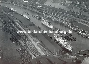 011_15293 - Luftaufnahme vom Hamburger Hafen; Seeschiffe liegen an der Kaimauer oder auf Reede und werden entladen; Lagerschuppen sumen die Kaimauer und Schuten warten auf ihre Ladung - historisches Motiv vom Baakenhafen ca. 1930