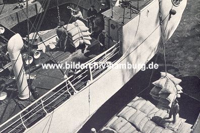 011_15298 - ein Kran ldt seine Ladung Scke auf einer lngsseits liegenden Schute - vorher wird die Ladung an Bord von Hafenarbeitern gewogen. (ca. 1952)