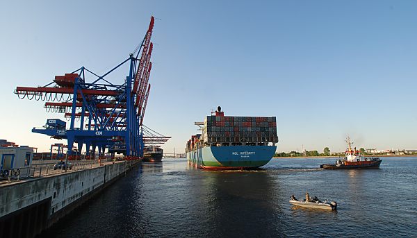 011_15588 - die Containerbrcken vom Schiffsliegeplatz sind hochgeklappt - das hochbeladene Frachtschiff legt ab; ein kleines Sportboot beobachtet das Manver. 