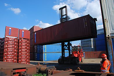 011_15717 - der Container wird hochgefahren; ein Arbeiter mit Signalkleidung / Sicherheitskleidung und Helm gibt ber Sprechfunk dem Fahrer vom Greifstapler Anweisungen.